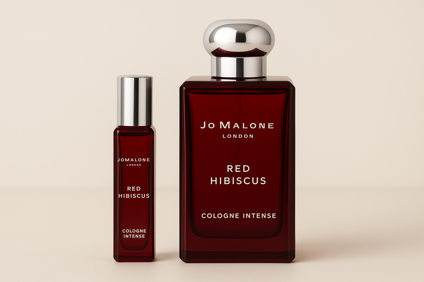 Jo Malone Red Hibiscus Cologne Intense דוגמית 12 מ"ל עומדת ליד בקבוק בושם 100 מ"ל של Jo Malone Red Hibiscus Cologne Intense עם כתובה לבנה על בקבוק אדום כהה