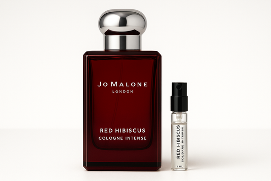 Jo Malone Red Hibiscus Cologne Intense דוגמית 1 מ"ל עומדת ליד בקבוק בושם 100 מ"ל של Jo Malone Red Hibiscus Cologne Intense עם כתובה לבנה על בקבוק אדום כהה